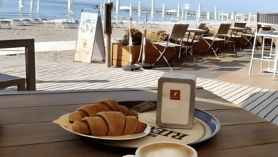 A cappuccino and croissants on a table overlooking the beach with umbrellas and the sea in Eraclea Mare, Italy.