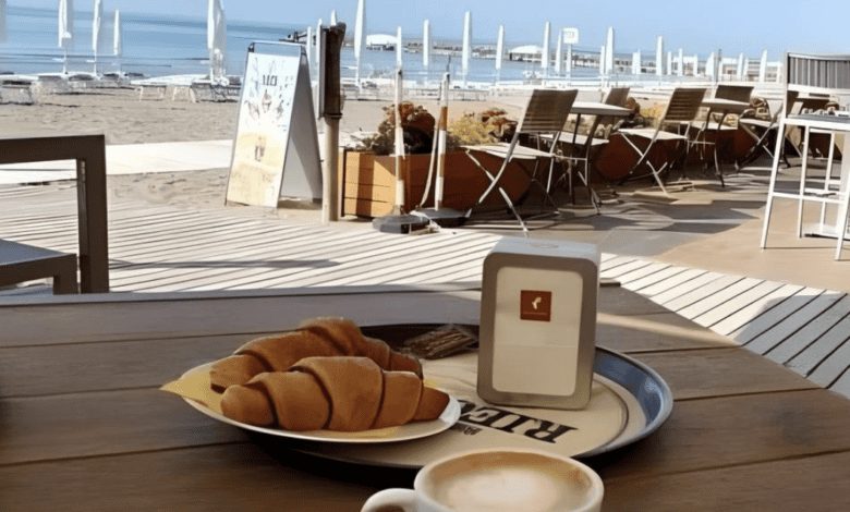 A cappuccino and croissants on a table overlooking the beach with umbrellas and the sea in Eraclea Mare, Italy.