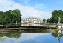 A front view of the grand Villa Pisani in Italy, with its symmetrical reflection in the calm water in the foreground.